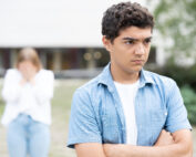 An angry and serious adolescent walks away from his friend.