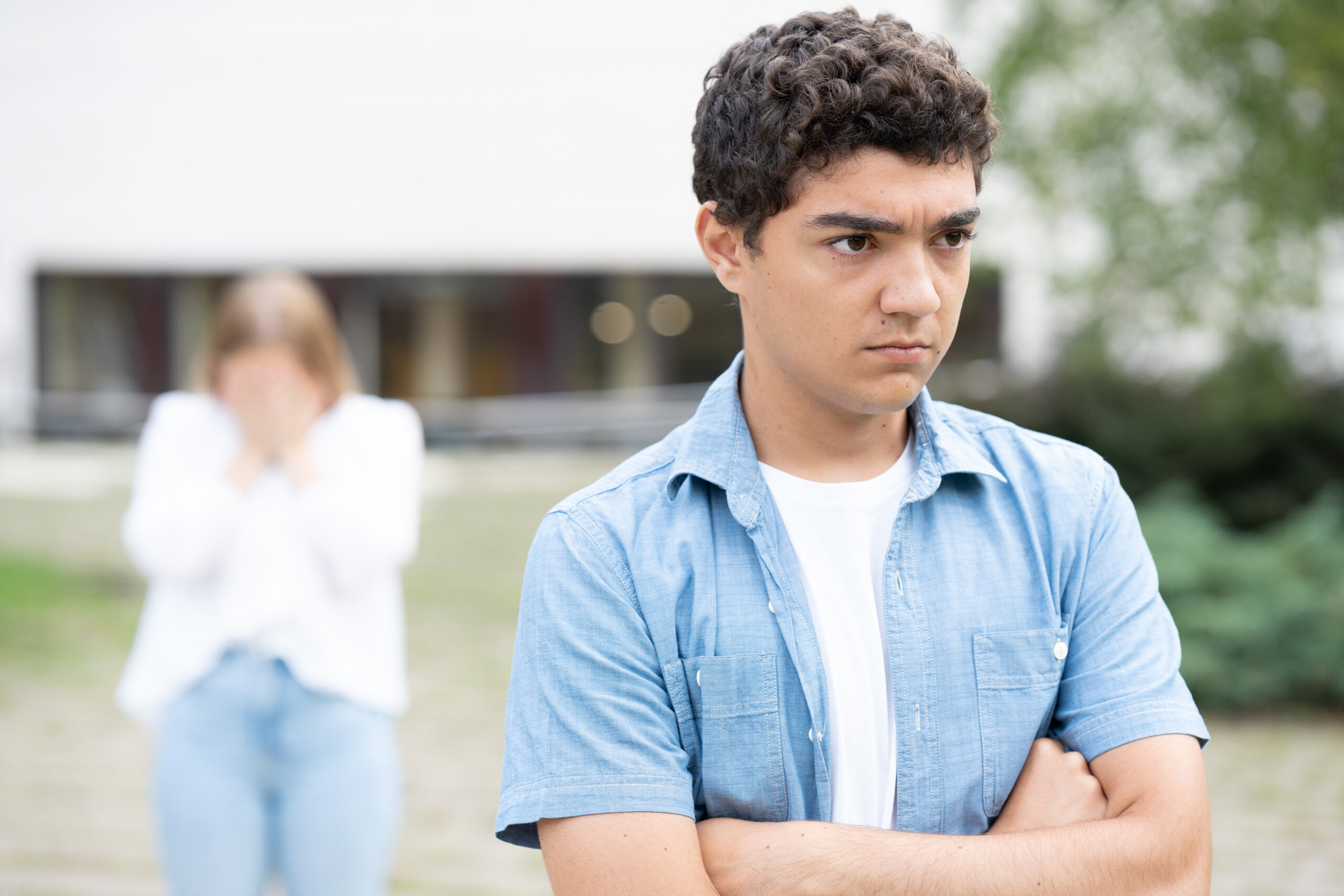 An angry and serious adolescent walks away from his friend.