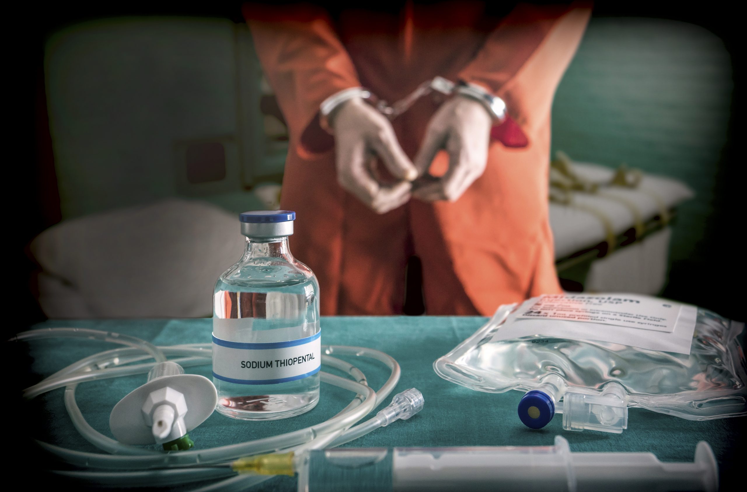 Prisoner handcuffed to death by lethal injection, vial with sodium thiopental and syringe on top of a table, conceptual image