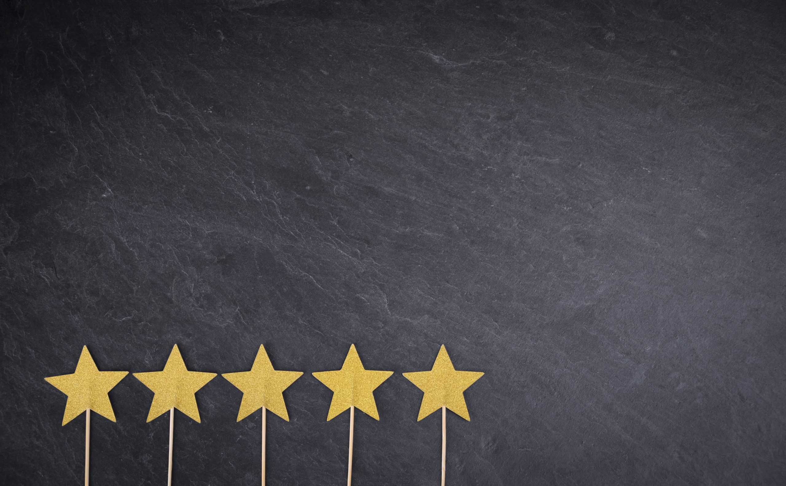 Five golden stars on slate background as symbol for rating