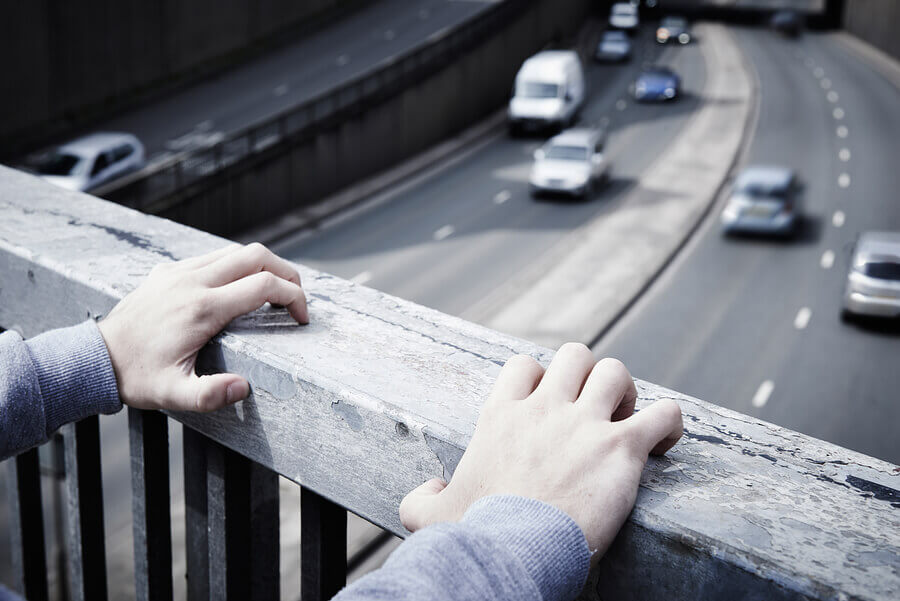 Depressed Young Man Contemplating Suicide On Road Bridge