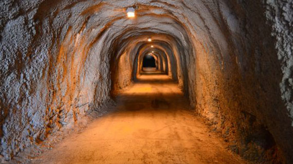 An old illuminated underground tunnel stretching into the darkness