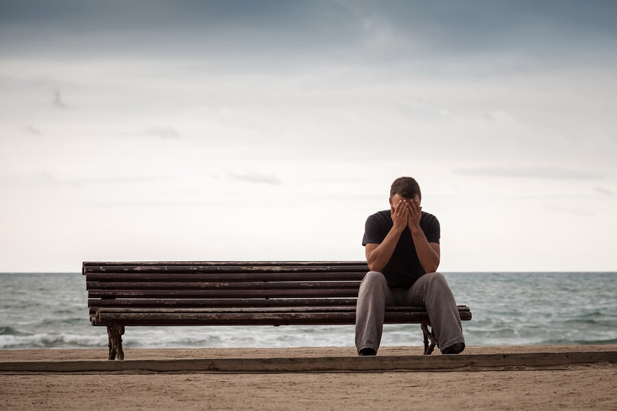 Sad Man Sits On An Old Wooden Bench On The Sea Coast