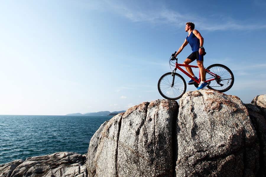 Young Athlete Standing on Top of a Mountain with Bicycle