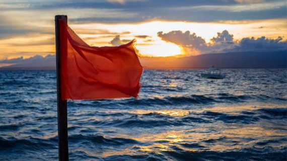 Red flag by the sea with sunset background