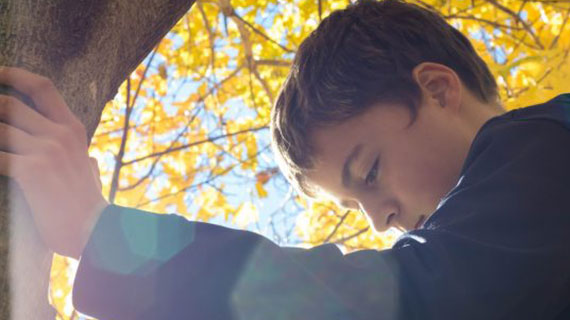 teen boy leaning on tree